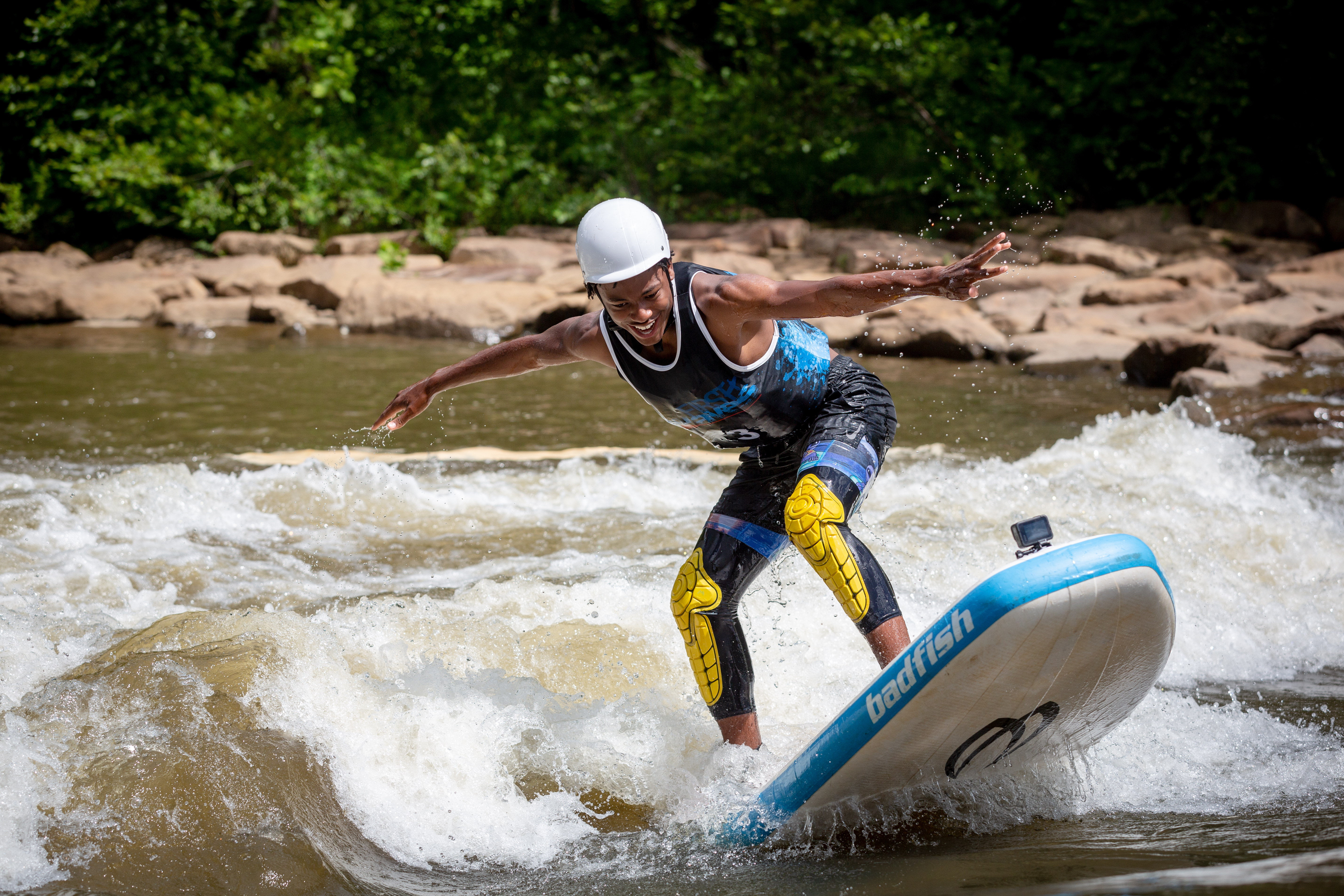 A youth surfs a river wave while smiling